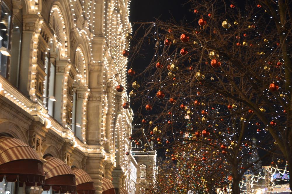 Commercial building facade covered in warm white Christmas lights with red and gold ornaments
